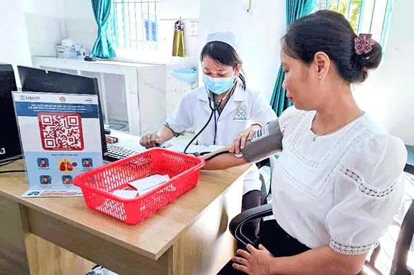Nhân viên y tế đo huyết áp miễn phí cho người dân tại trạm y tế.